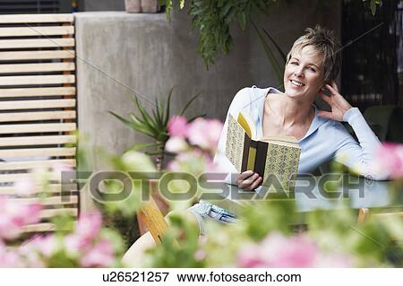 Portrait of a mature woman holding a book and smiling View Large Photo Image Stock Photo - Portrait of a mature woman holding a book and smiling. Fotosearch