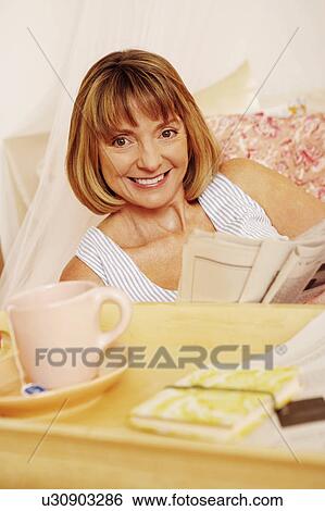 Portrait of a mature woman holding a newspaper and smiling View Large Photo Image Stock Photograph - Portrait of a mature woman holding a newspaper and smiling. Fotosearch