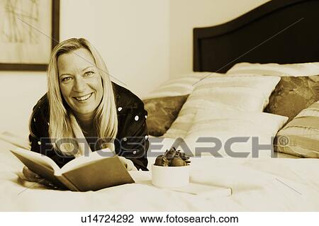 Portrait of a mature woman lying on the bed with a book and smiling View Large Photo Image Stock Image - Portrait of a mature woman lying on the bed with a book and smiling. Fotosearch