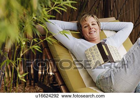 Stock Image - Portrait of a mature woman reclining on a lounge chair. Fotosearch