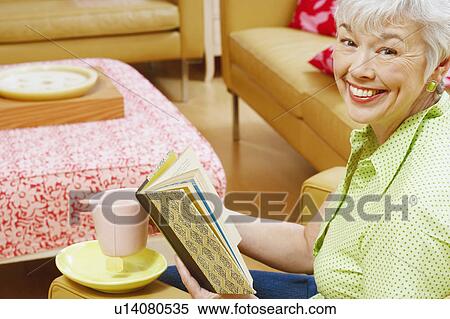 Stock Photography - Portrait of a senior woman holding a book and smiling. Fotosearch