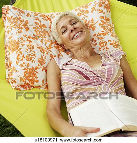 Stock Image - Portrait of a senior woman lying in a hammock and smiling. Fotosearch