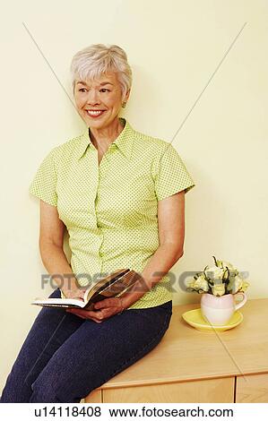 Senior woman holding a book and smiling View Large Photo Image Stock Photo - Senior woman holding a book and smiling. Fotosearch