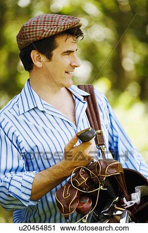 Stock Image - Close-up of a mature man carrying a golf bag. Fotosearch