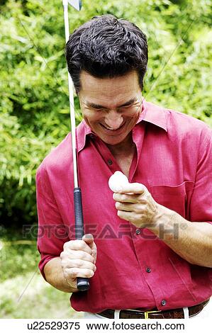 Stock Photography - Close-up of a mature man holding a golf club and a golf ball. Fotosearch