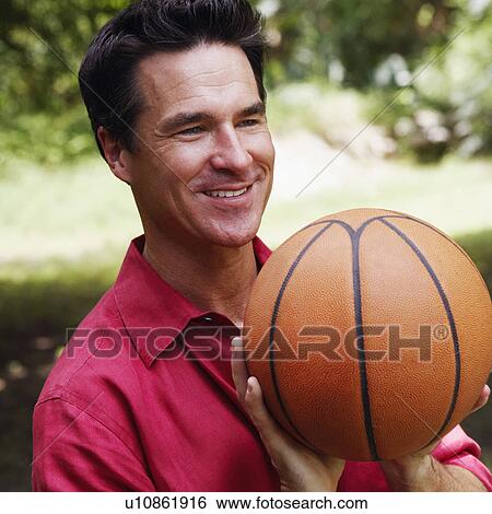 Stock Photograph - Close-up of a mature man holding a basketball. Fotosearch