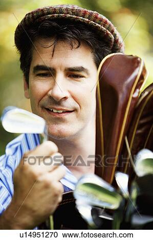 Stock Image - Close-up of a mature man looking at a golf club. Fotosearch