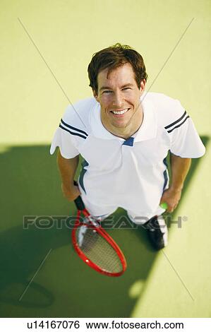 Stock Photograph - High angle view of a mid adult man holding a tennis racket. Fotosearch