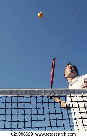 Stock Photo - Low angle view of a mid adult man playing tennis. Fotosearch