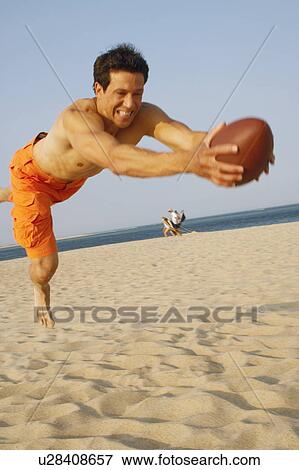 Stock Photo - Mature man playing football on the beach. Fotosearch