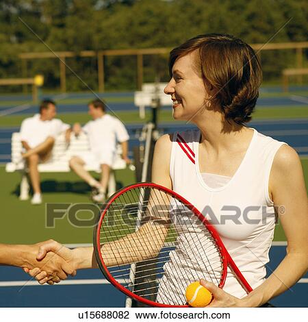 Mid adult woman shaking hands with a woman on a tennis court View Large Photo Image Stock Image - Mid adult woman shaking hands with a woman on a tennis court. Fotosearch