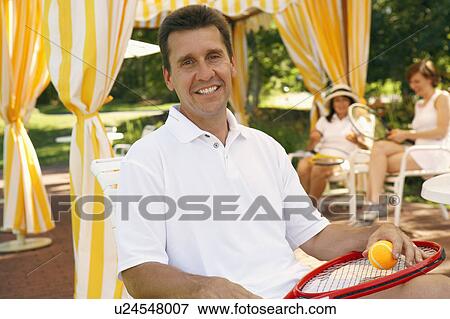 Portrait of a mature man sitting on a chair and holding a tennis ball and a tennis racket View Large Photo Image Stock Photo - Portrait of a mature man sitting on a chair and holding a tennis ball and a tennis racket. Fotosearch
