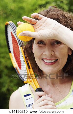 Portrait of a mature woman holding a tennis ball and a tennis racket View Large Photo Image Stock Image - Portrait of a mature woman holding a tennis ball and a tennis racket. Fotosearch