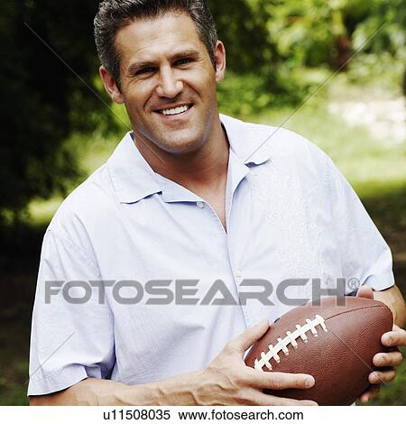 Portrait of a mid adult man holding a football View Large Photo Image Stock Photography - Portrait of a mid adult man holding a football. Fotosearch