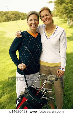 Stock Photo - Portrait of a mid adult woman and a mature woman holding golf clubs. Fotosearch