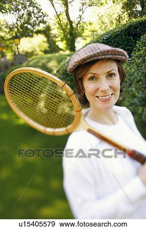 Portrait of a mid adult woman holding a tennis racket and smiling View Large Photo Image Stock Photo - Portrait of a mid adult woman holding a tennis racket and smiling. Fotosearch
