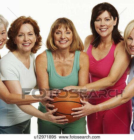 Stock Photography - Portrait of five mature women holding a basketball and smiling. Fotosearch