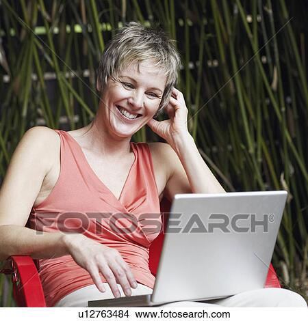 Picture - Close-up of a mature woman using a laptop. Fotosearch
