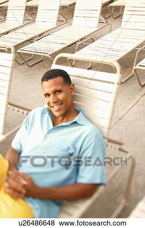 Stock Photo - High angle view of a mature man reclining on a lounge chair. Fotosearch