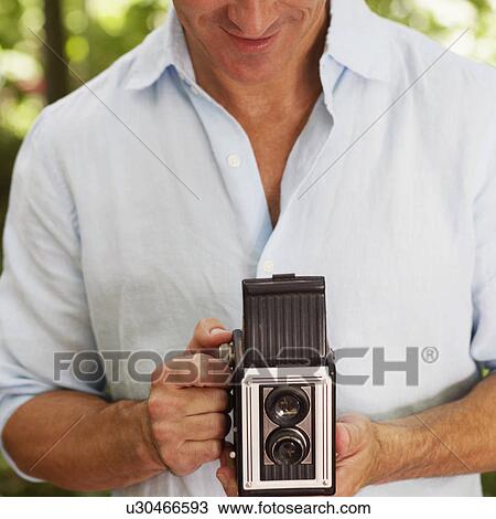 Stock Image - Mature man holding a camera. Fotosearch