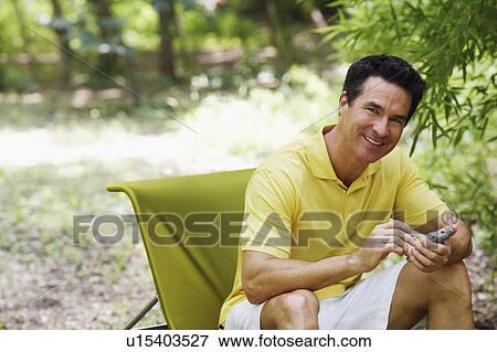 Stock Photo - Mature man using a personal data assistant. Fotosearch
