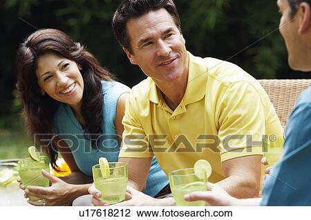 Stock Image - Mature woman and two mature men holding glasses of lemonade. Fotosearch