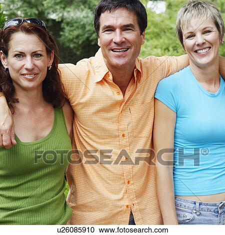 Stock Image - Portrait of a mature man and two mature women standing together and smiling. Fotosearch