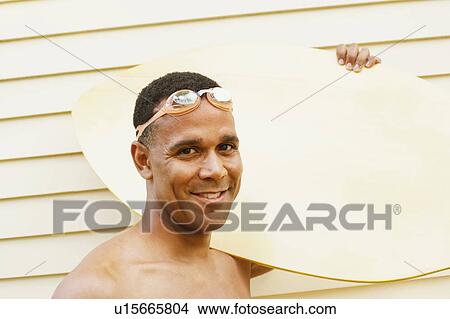 Portrait of a mature man carrying a surfboard and smiling View Large Photo Image Picture - Portrait of a mature man carrying a surfboard and smiling. Fotosearch
