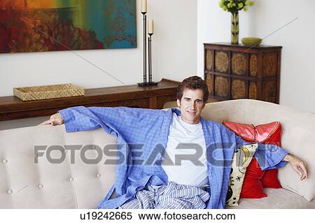 Stock Photography - Portrait of a mature man resting on a couch and smiling. Fotosearch