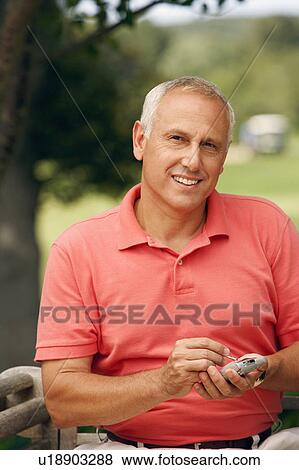 Portrait of a mature man using a personal data assistant in a park View Large Photo Image Stock Photo - Portrait of a mature man using a personal data assistant in a park. Fotosearch
