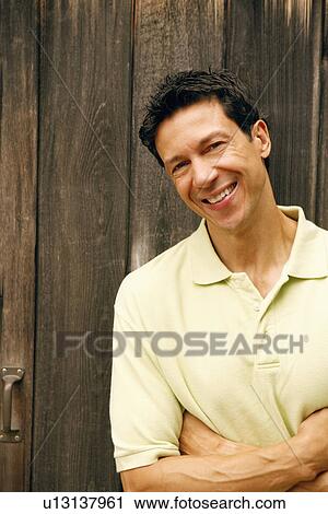 Stock Image - Portrait of a mature man with his arms crossed smiling. Fotosearch