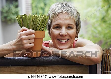 Stock Photo - Portrait of a mature woman leaning on a gate and smiling. Fotosearch