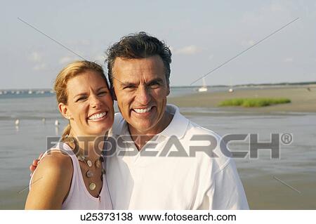 Portrait of a mid adult woman and a mature man standing on the beach and smiling View Large Photo Image Stock Photo - Portrait of a mid adult woman and a mature man standing on the beach and smiling. Fotosearch