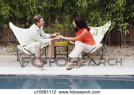 Stock Image - Side profile of a mature man holding the hand of a mature woman. Fotosearch