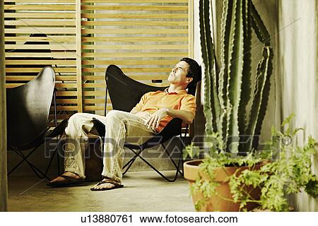 Stock Image - Side profile of a mature man sitting on a chair and sleeping. Fotosearch