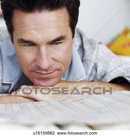 Close-up of a mature man lying on the bed and reading a newspaper View Large Photo Image Stock Image - Close-up of a mature man lying on the bed and reading a newspaper. Fotosearch