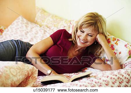 Close-up of a mature woman lying on the bed reading a book View Large Photo Image Stock Photo - Close-up of a mature woman lying on the bed reading a book. Fotosearch