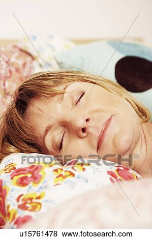 Stock Photo - Close-up of a mature woman sleeping on the bed. Fotosearch