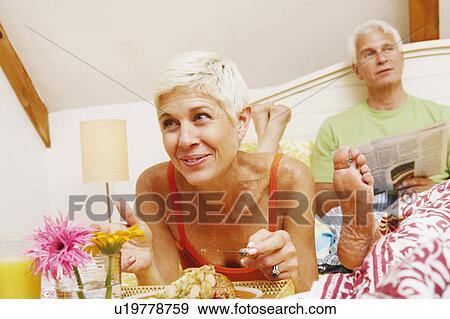 Close-up of a senior woman having breakfast in bed with a mature man sitting behind her View Large Photo Image Stock Photo - Close-up of a senior woman having breakfast in bed with a mature man sitting behind her. Fotosearch