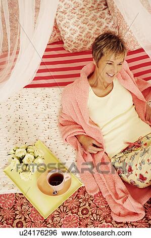 High angle view of a mature woman reclining on the bed and smiling View Large Photo Image Stock Photograph - High angle view of a mature woman reclining on the bed and smiling. Fotosearch