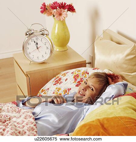 Stock Photography - Portrait of a mature woman lying in bed and smiling. Fotosearch