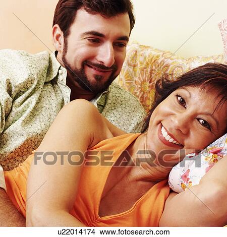 Portrait of a mature woman smiling with a mature man lying behind her View Large Photo Image Picture - Portrait of a mature woman smiling with a mature man lying behind her. Fotosearch