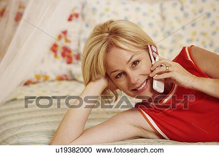 Stock Image - Portrait of a mature woman talking on a flip phone and smiling. Fotosearch