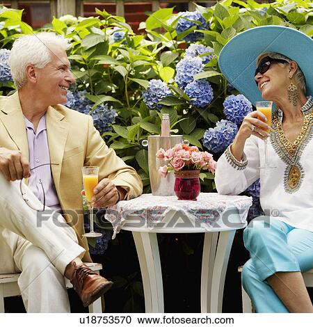 Close-up of a mature man and a senior woman sitting together and holding glasses of juice View Large Photo Image Stock Image - Close-up of a mature man and a senior woman sitting together and holding glasses of juice. Fotosearch