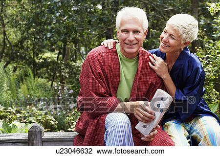 Stock Image - Close-up of a mature man and a senior woman sitting together and smiling. Fotosearch