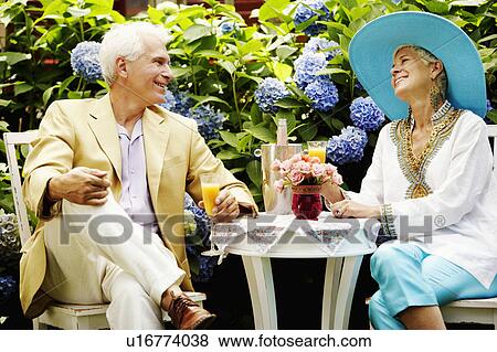 Close-up of a mature man and a senior woman sitting together and holding glasses of juice View Large Photo Image Stock Photo - Close-up of a mature man and a senior woman sitting together and holding glasses of juice. Fotosearch