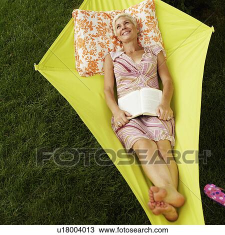 High angle view of a senior woman holding a book and lying in a hammock View Large Photo Image Stock Image - High angle view of a senior woman holding a book and lying in a hammock. Fotosearch