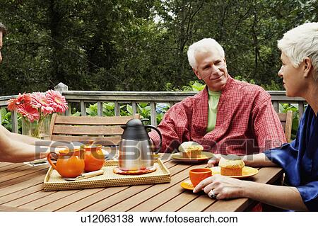 Stock Photo - Mature man and a senior woman sitting at the table and looking at each other. Fotosearch