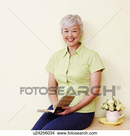 Portrait of a senior woman holding a book and smiling View Large Photo Image Picture - Portrait of a senior woman holding a book and smiling. Fotosearch