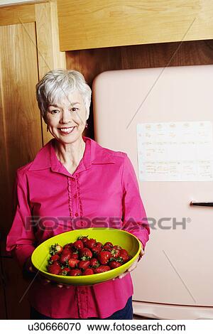 Portrait of a senior woman holding a bowl of strawberries View Large Photo Image Stock Image - Portrait of a senior woman holding a bowl of strawberries. Fotosearch